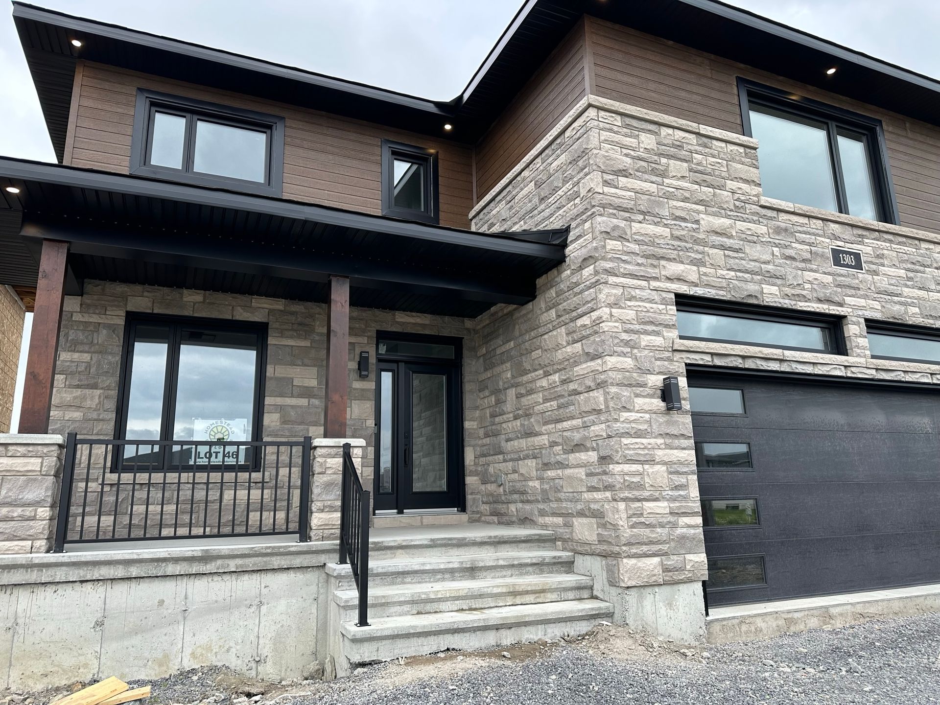 Une grande maison en briques avec une porte de garage noire et des escaliers