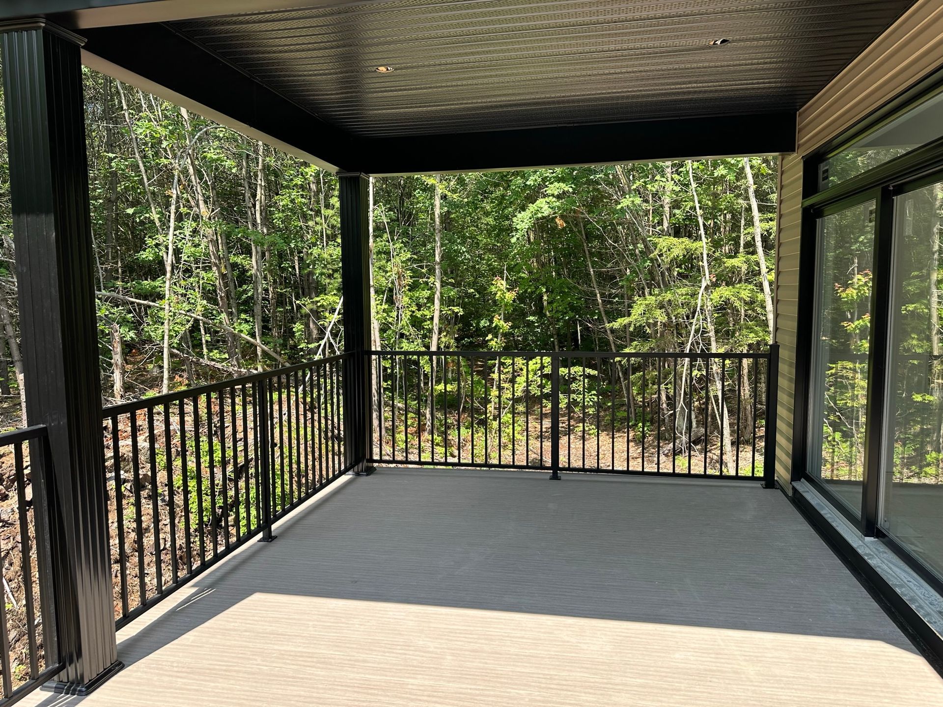 Un porche vide avec une balustrade noire et des arbres en arrière-plan.