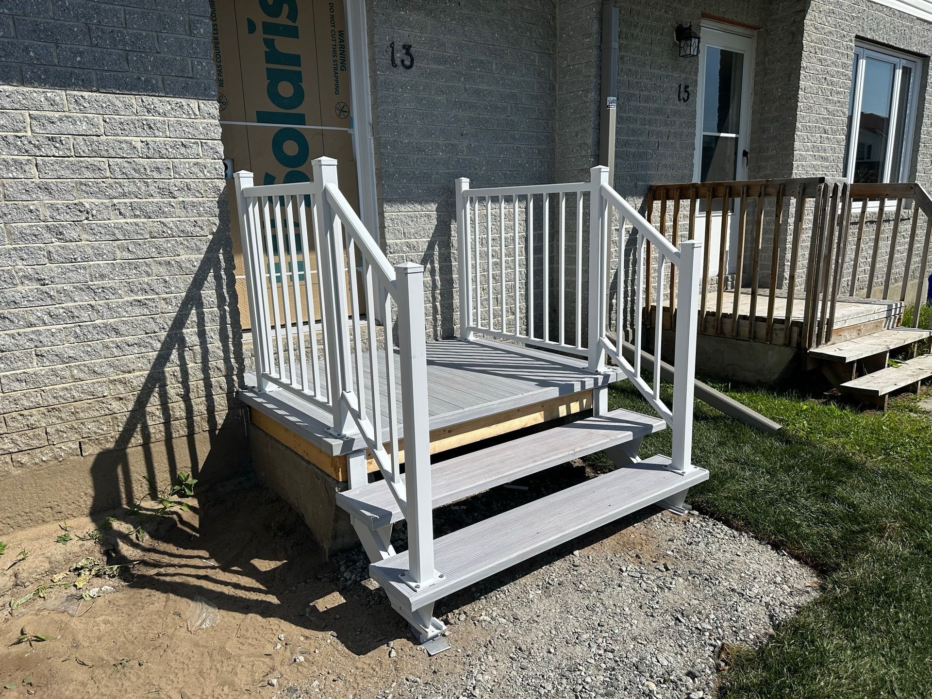 Un escalier menant à une maison avec une rampe blanche.