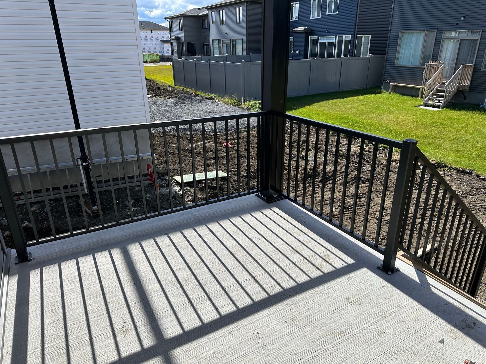 Un balcon avec une balustrade en métal et des escaliers menant à une maison.