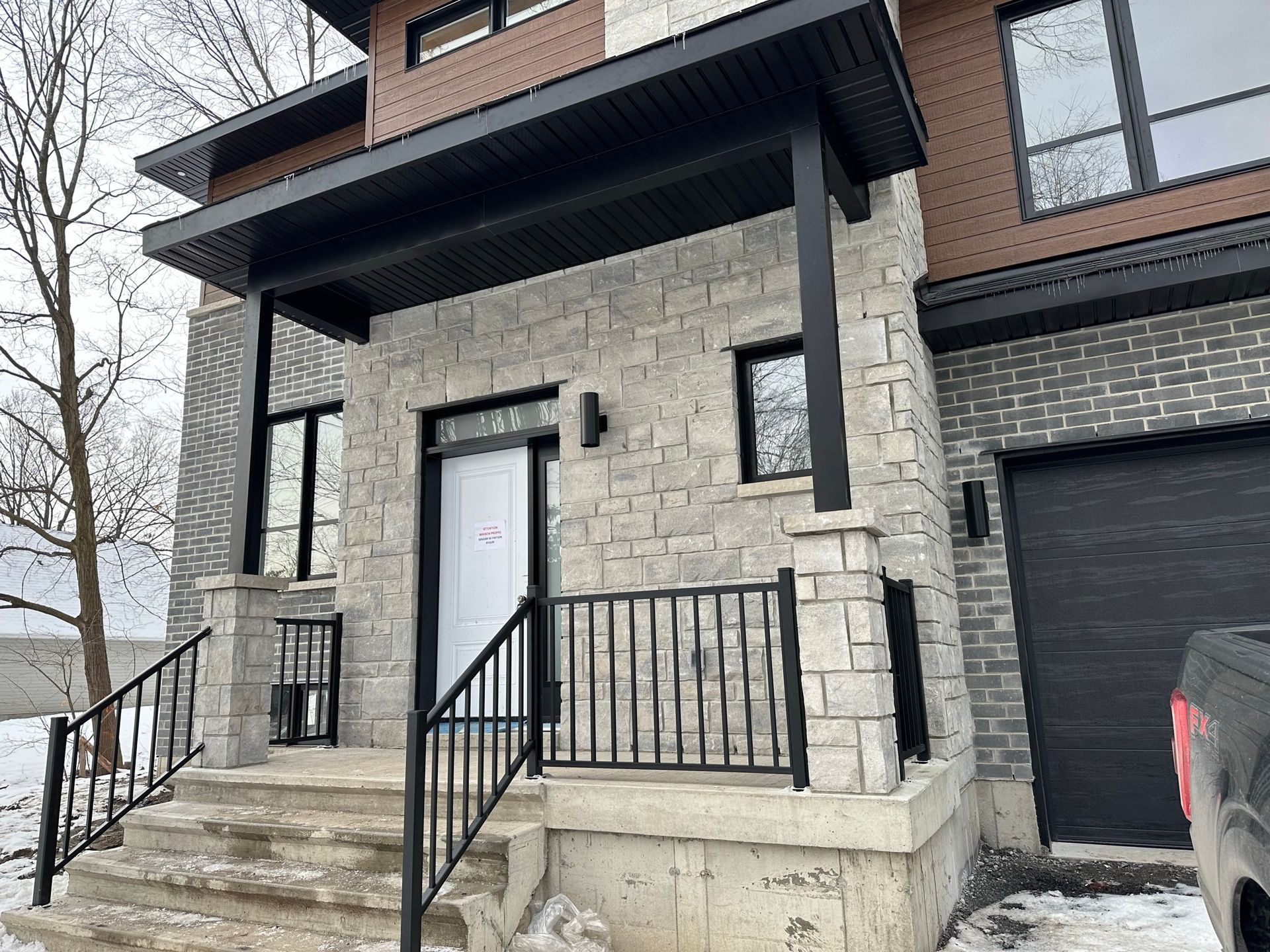 Une maison avec un porche et des escaliers et un camion garé devant.