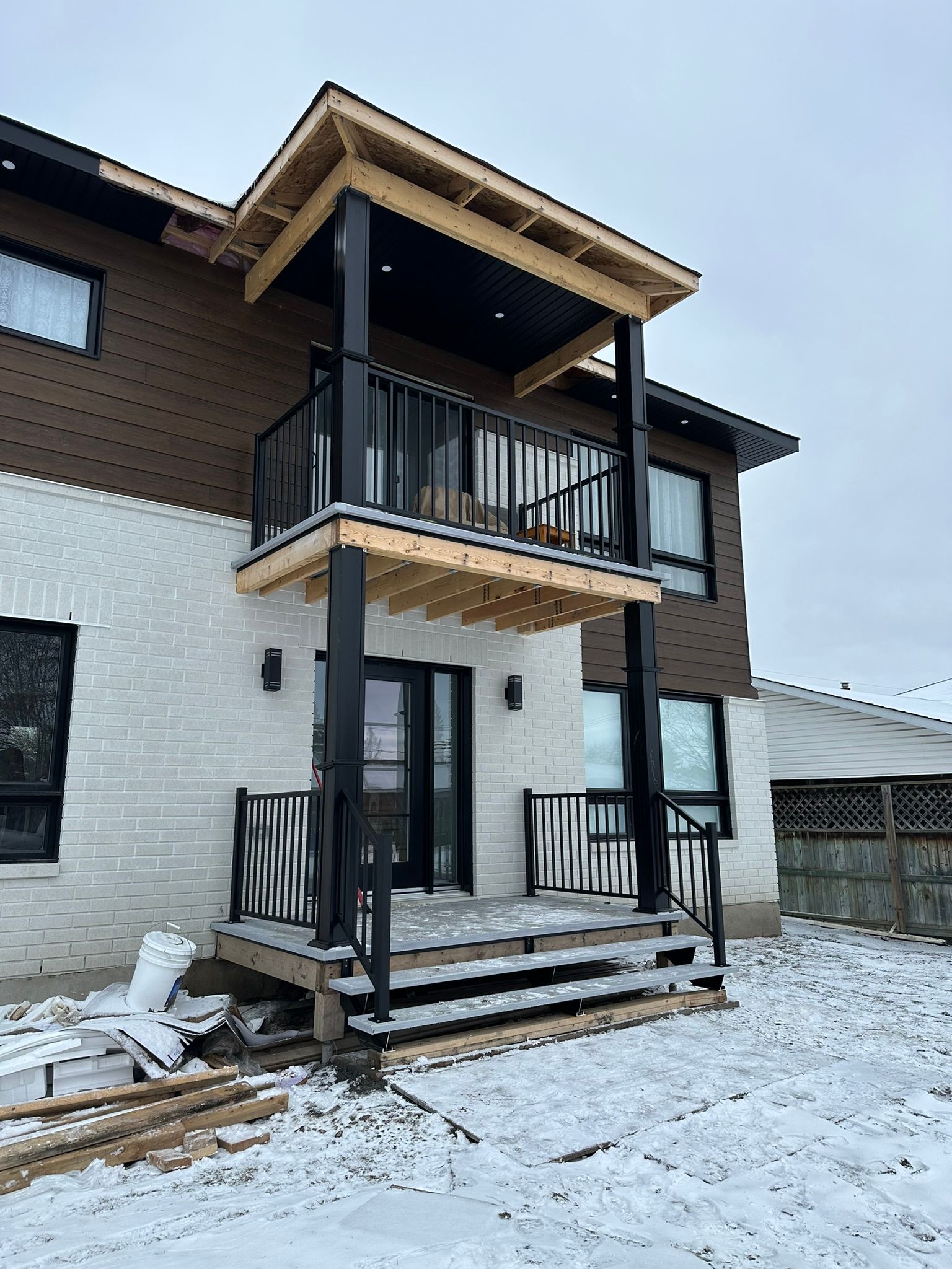 Une grande maison avec un balcon et des escaliers dans la neige.