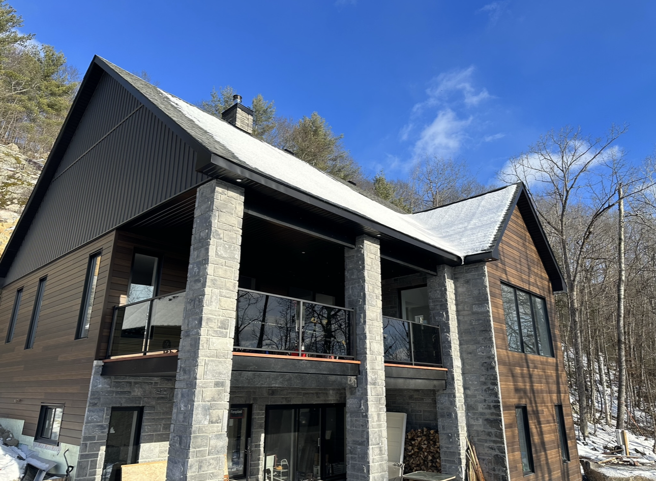 Une grande maison avec un balcon au milieu d'une forêt enneigée.