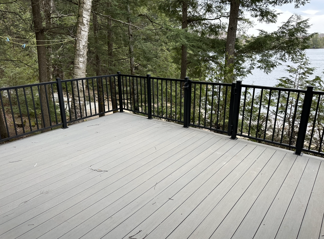 Une terrasse vide avec une balustrade noire donnant sur un lac.