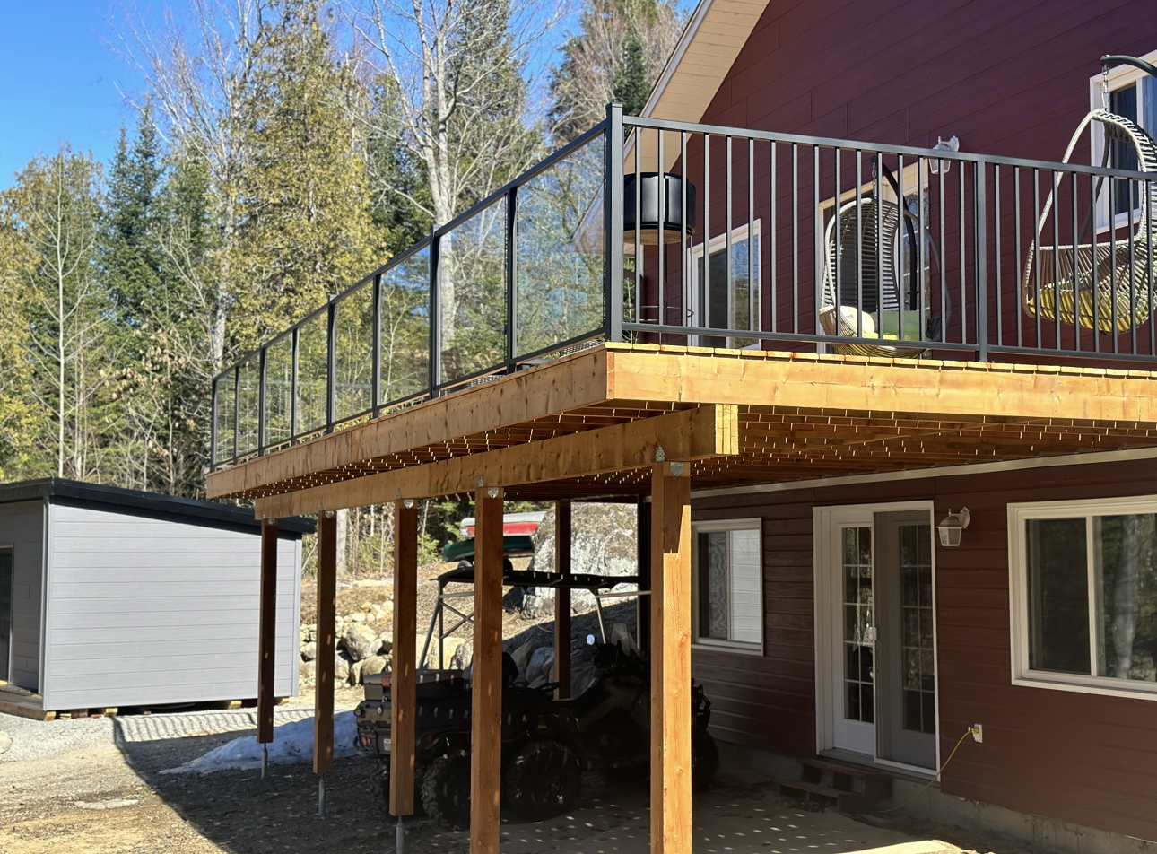 Une maison avec une terrasse et un abri voiture en dessous.