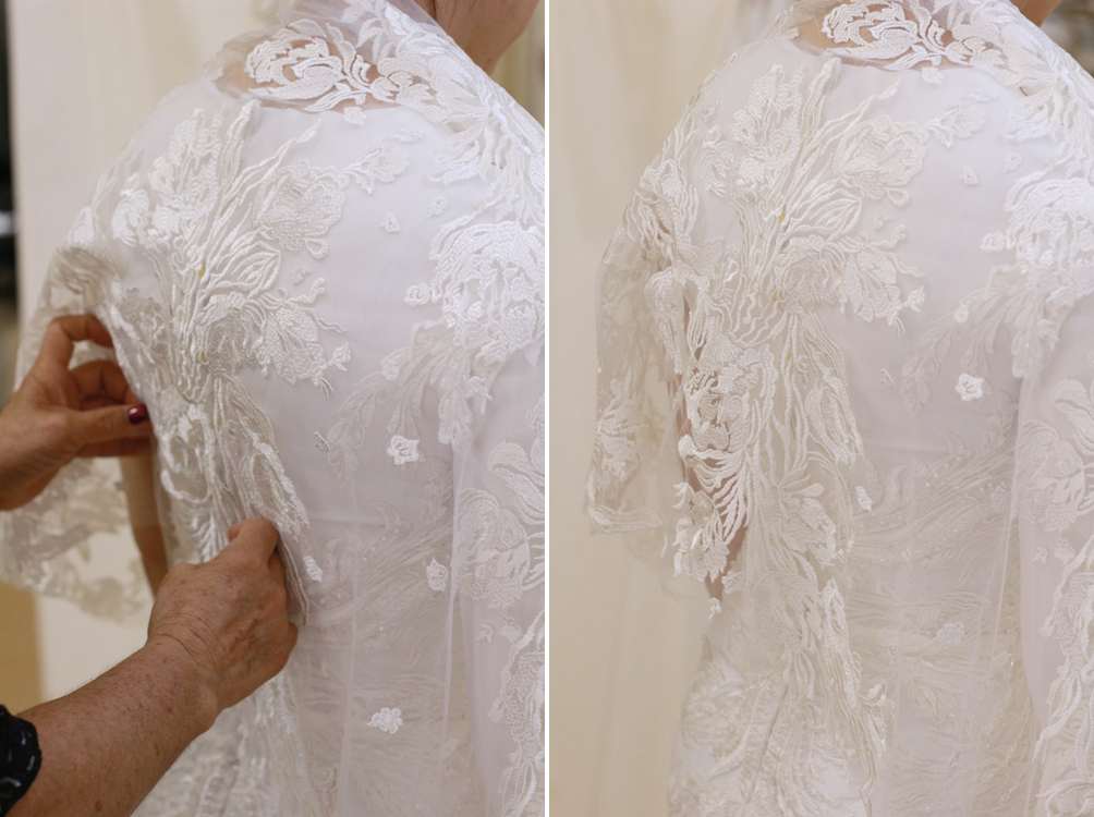 Person adjusting a white lace dress. Close-up on the back, with detailed floral embroidery.
