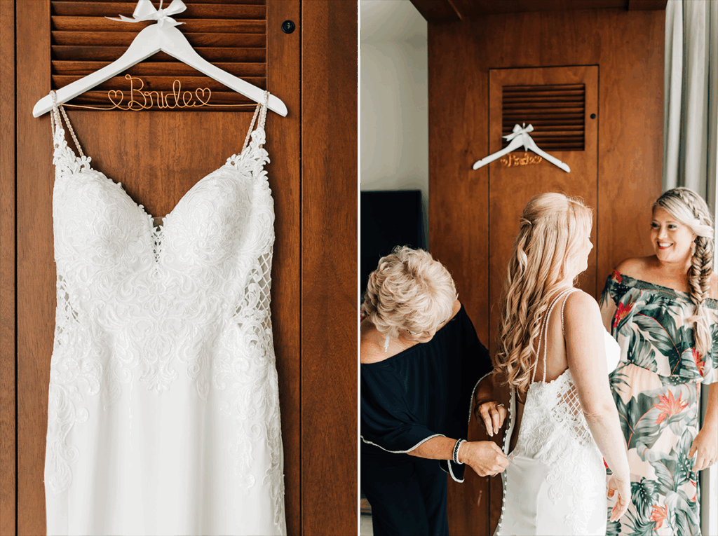 Wedding dress hanging on a wooden door, next to a bride being helped into her dress by two women.