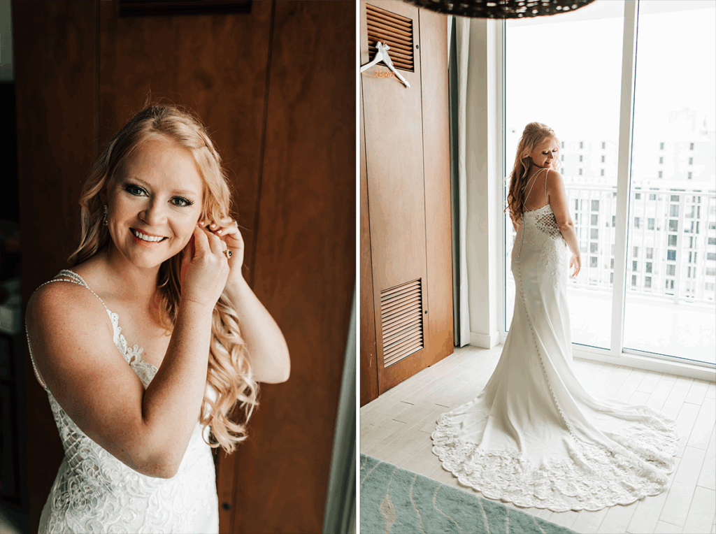 Bride adjusts earring, smiles. She wears a lace wedding dress, standing by a window.