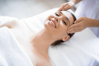 a woman is smiling while getting a head massage