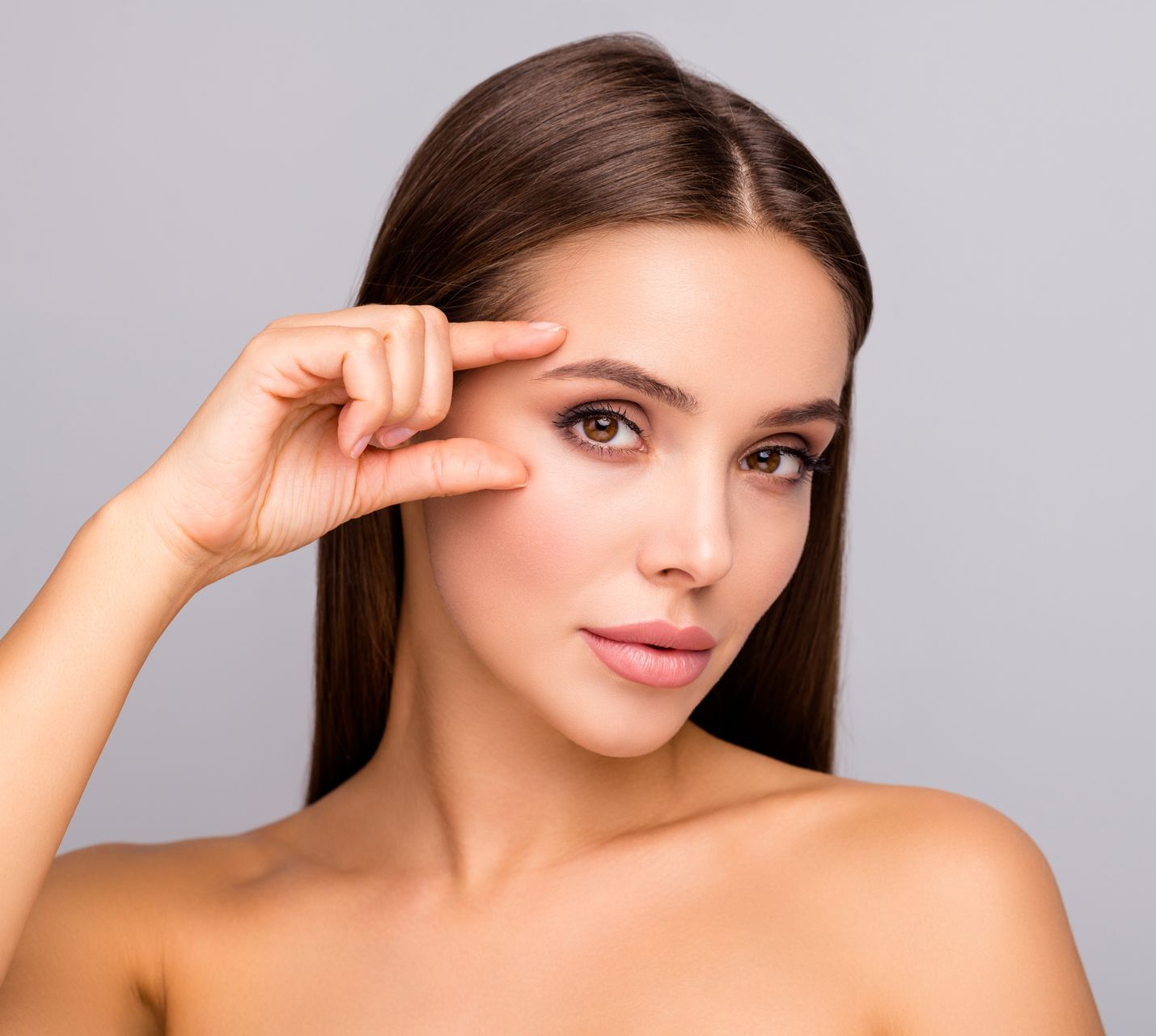 A woman is touching her eye with her finger.