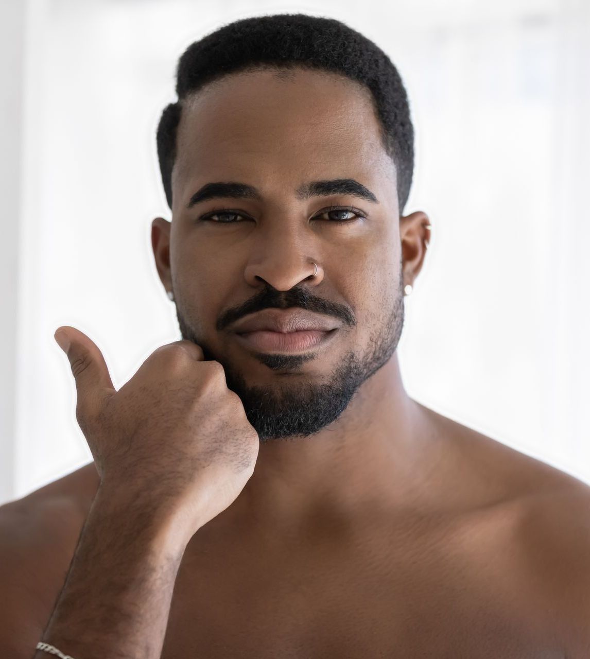 A shirtless man with a beard is giving a thumbs up sign.