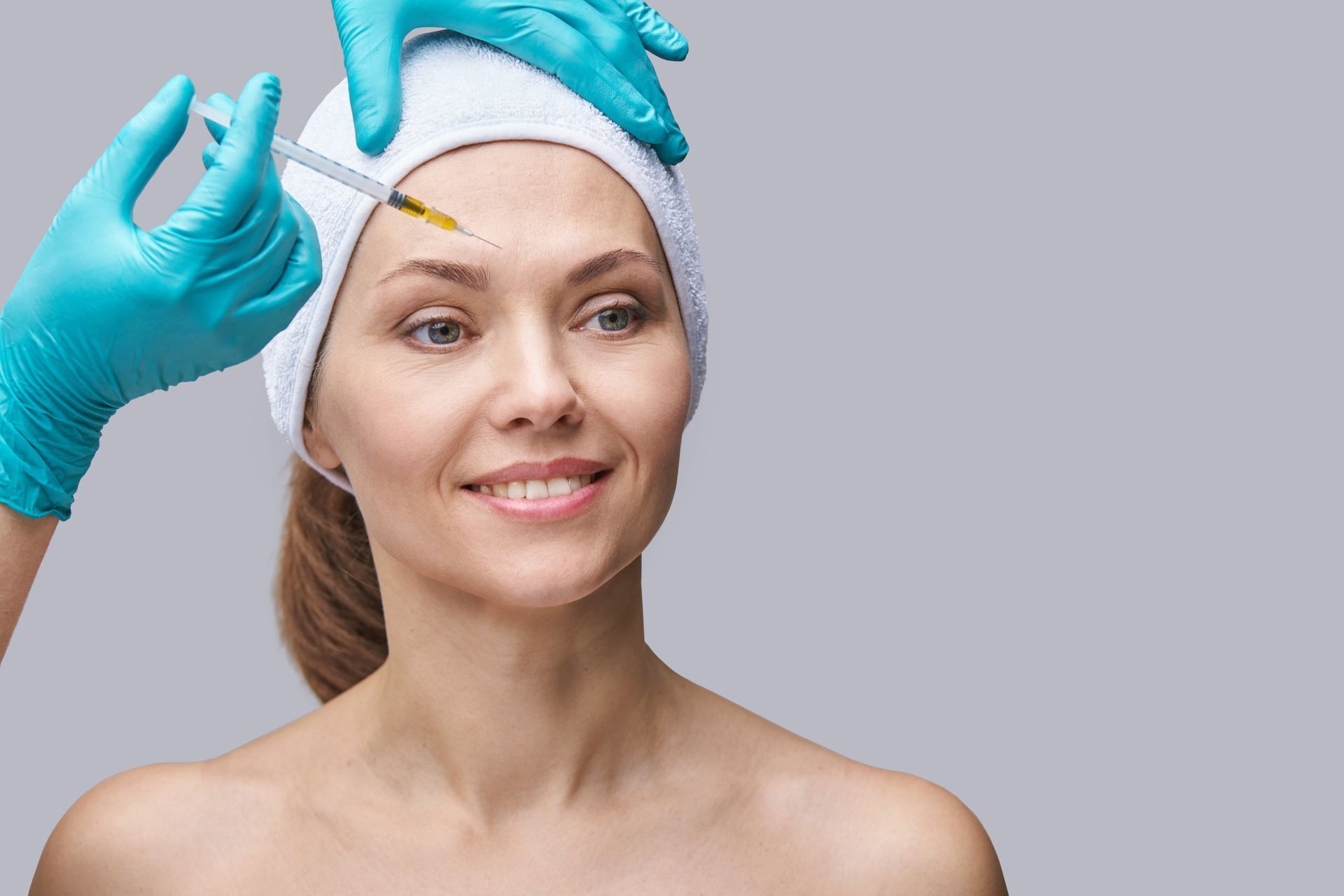 A woman is getting a botox injection in her forehead.