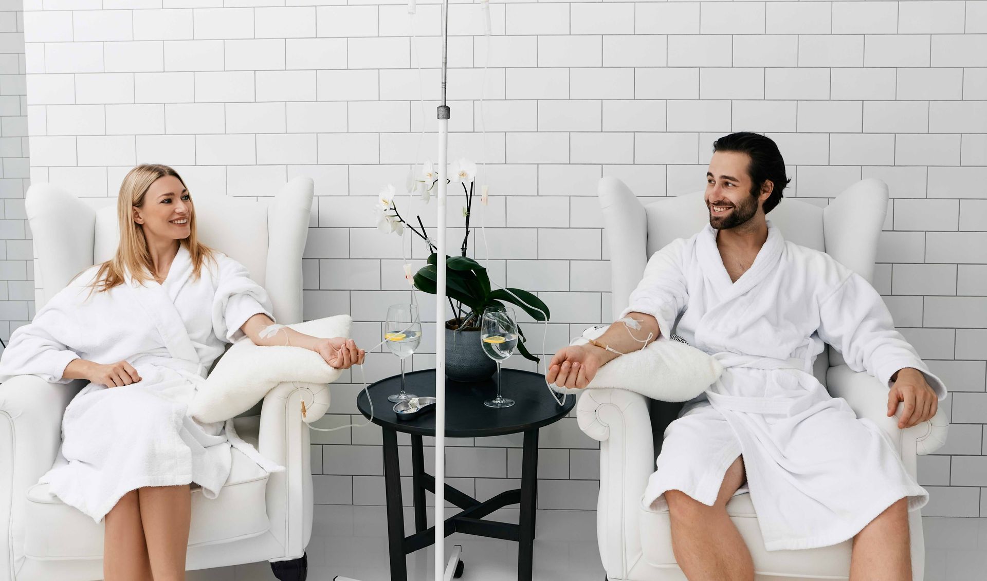 a man and a woman are sitting in chairs with iv drips in their hands