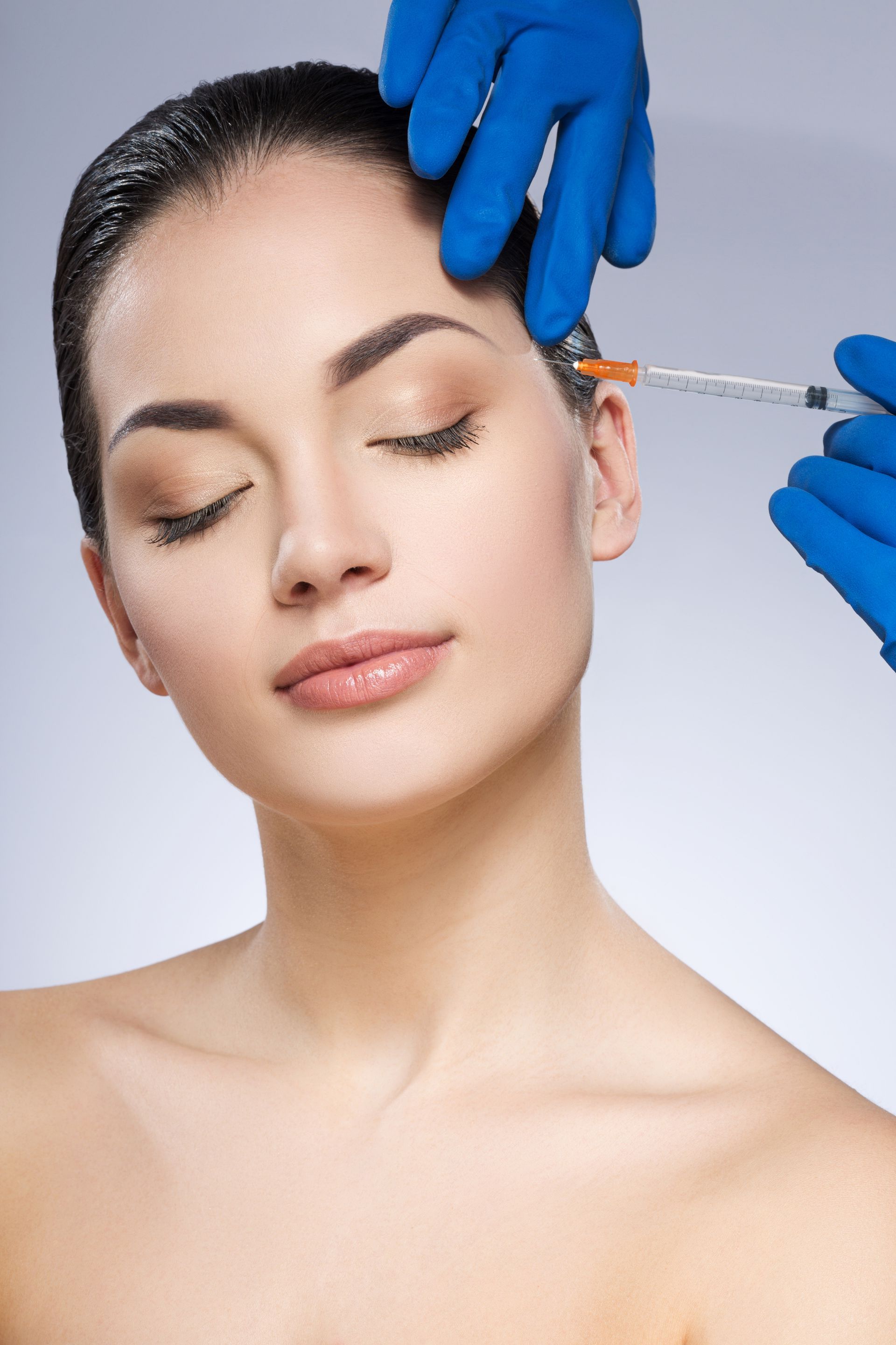 A woman is getting a botox injection in her forehead.