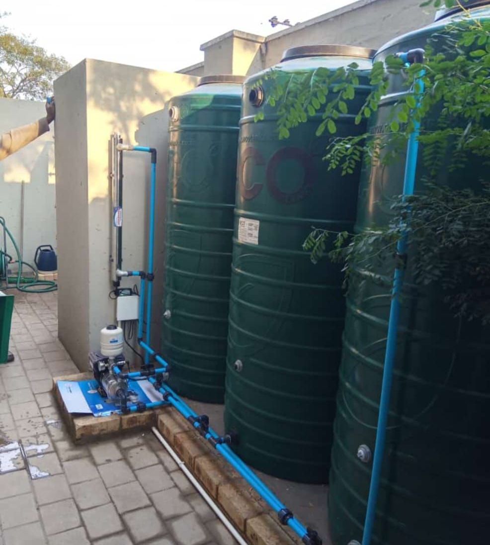 A person wearing rubber gloves is cleaning a stove with a cloth.