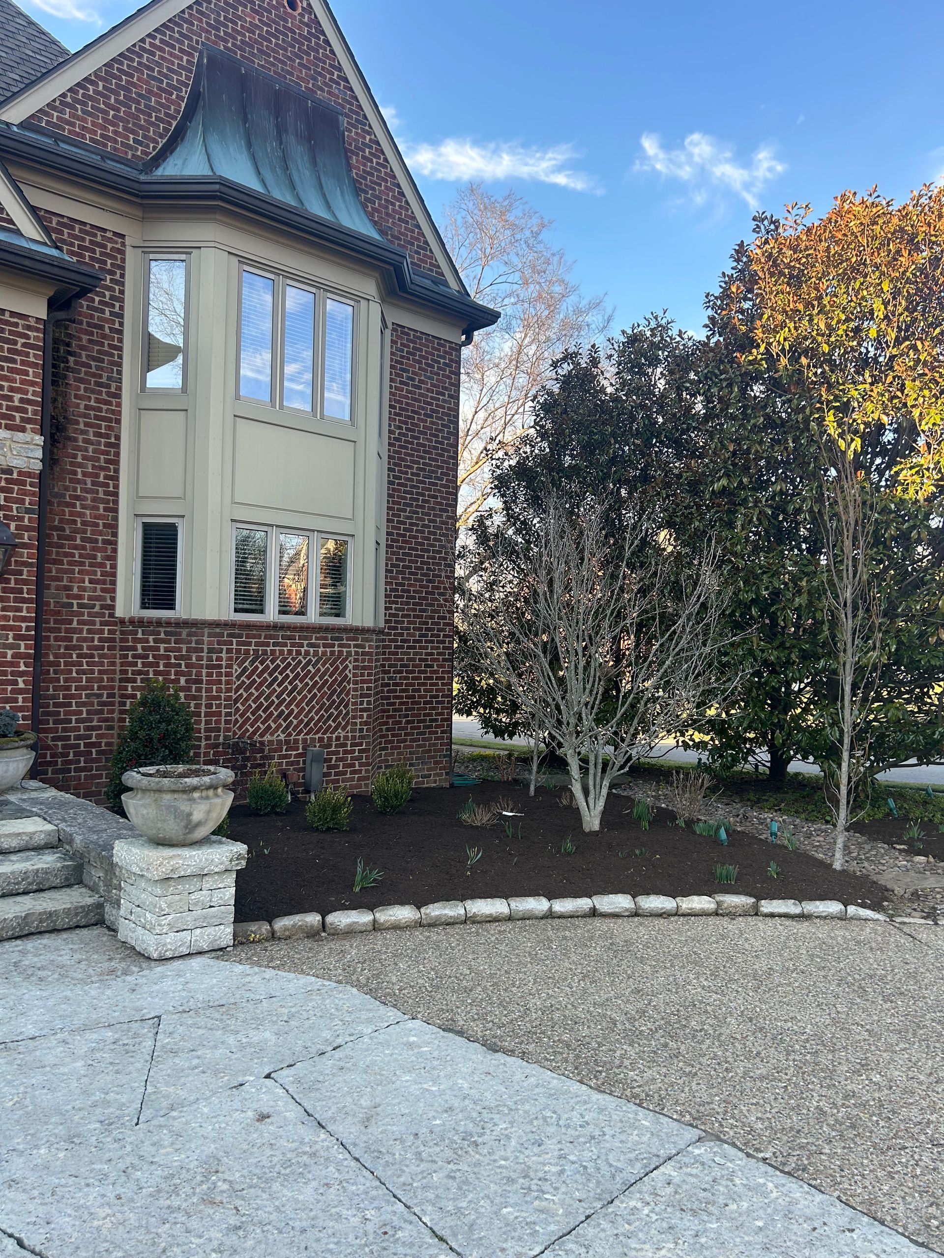 a large brick house with a gravel driveway in front of it . |  Nicholasville, KY | Grassy Lawns
