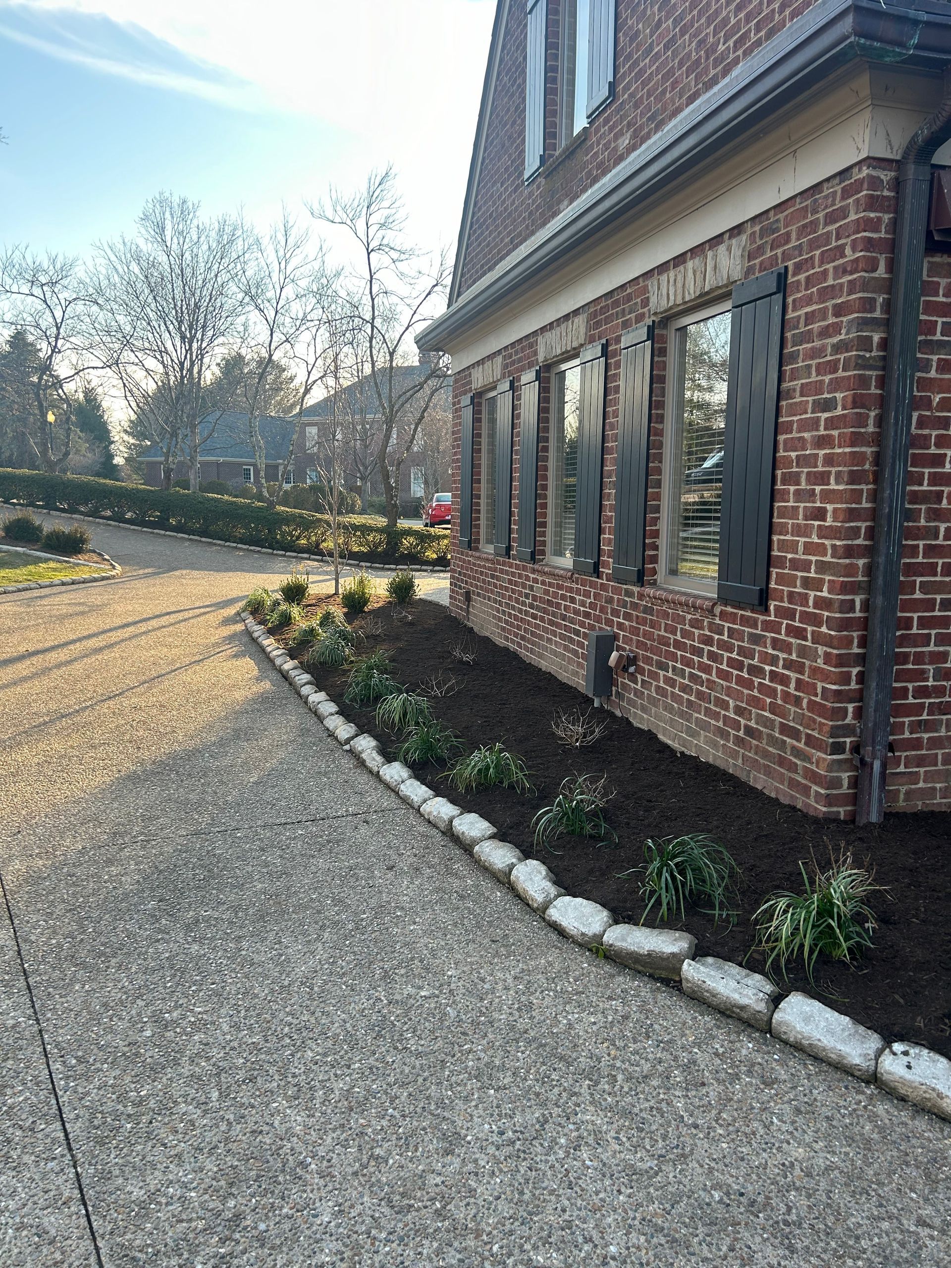 a brick house with a gravel driveway in front of it . |  Nicholasville, KY | Grassy Lawns

