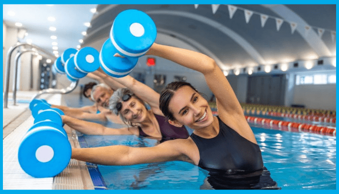 Group of adults smiling while using foam dumbbells in an aqua aerobics class, showing fitness and social benefits