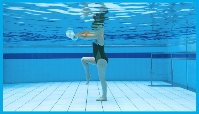 A woman is performing an aqua aerobics exercise underwater for weight loss and joint rehabilitation.