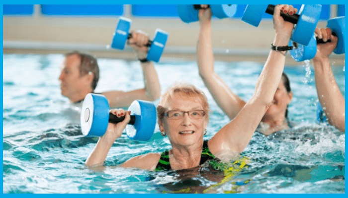 Smiling woman lifting foam dumbbells in an aqua aerobics class, showing the fun and low-impact benefits compared to land fitness