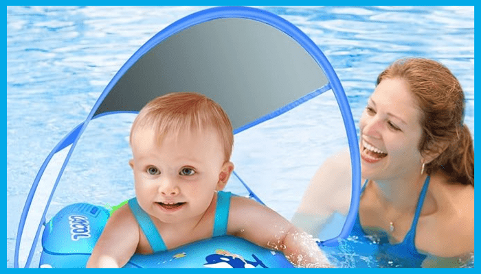 Smiling baby using a UPF50+ swimming float with canopy while a parent supervises in the pool, showing safe summer water play in Australia.