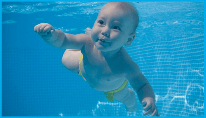 Baby confidently swimming underwater in a pool with eyes open and a calm expression.