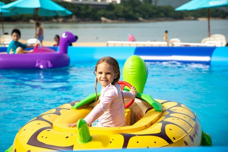 A female kid smiling in the camera while floating in the pool