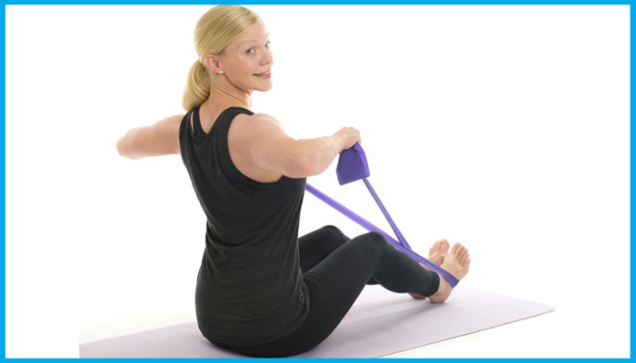Woman performing seated resistance band rows on a yoga mat to strengthen upper back, shoulders, and arms for swimming stroke power.