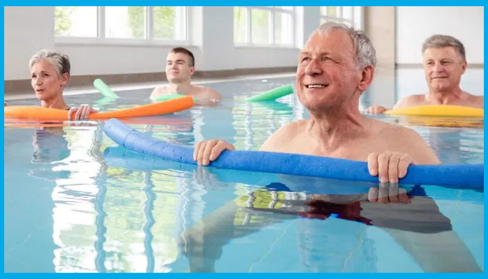 Older adults and younger participants using pool noodles during an aqua aerobics class in a swimming pool