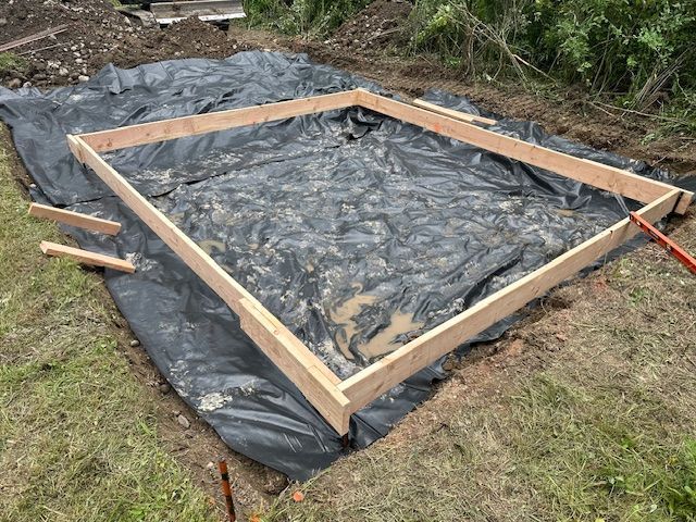 A wooden frame is sitting on top of a black tarp.