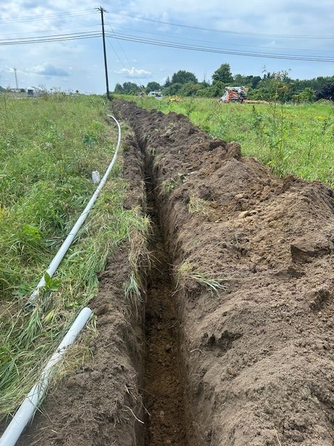 A trench in the middle of a field with a hose coming out of it.
