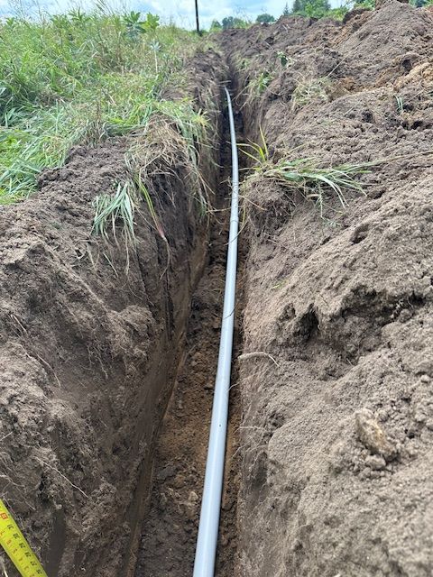 A pipe is being installed in a trench in the dirt.