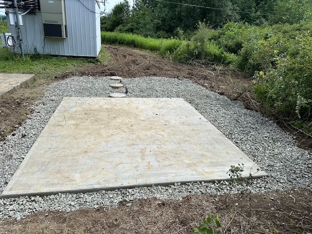 A large concrete slab is sitting in the middle of a gravel area.