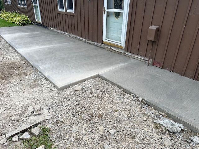A concrete walkway is being built in front of a brown house.