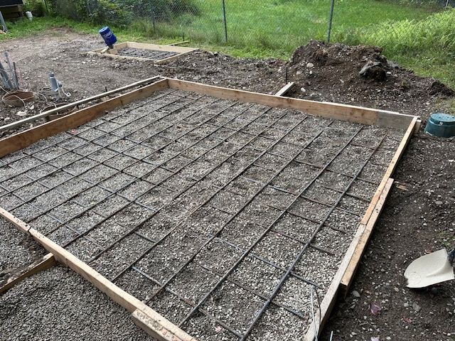 A concrete foundation is being built in a backyard.
