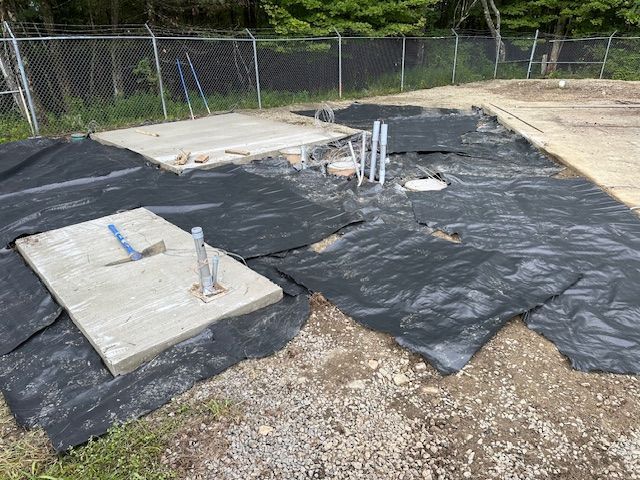 A concrete slab is sitting on top of a pile of black plastic.