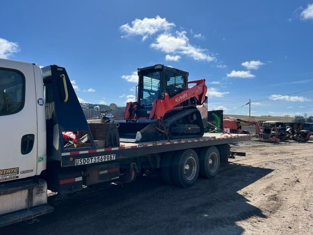 A tow truck is carrying a bulldozer on a flatbed trailer.