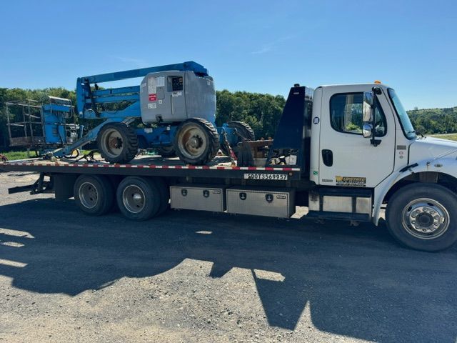 A tow truck is carrying a crane on the back of it.
