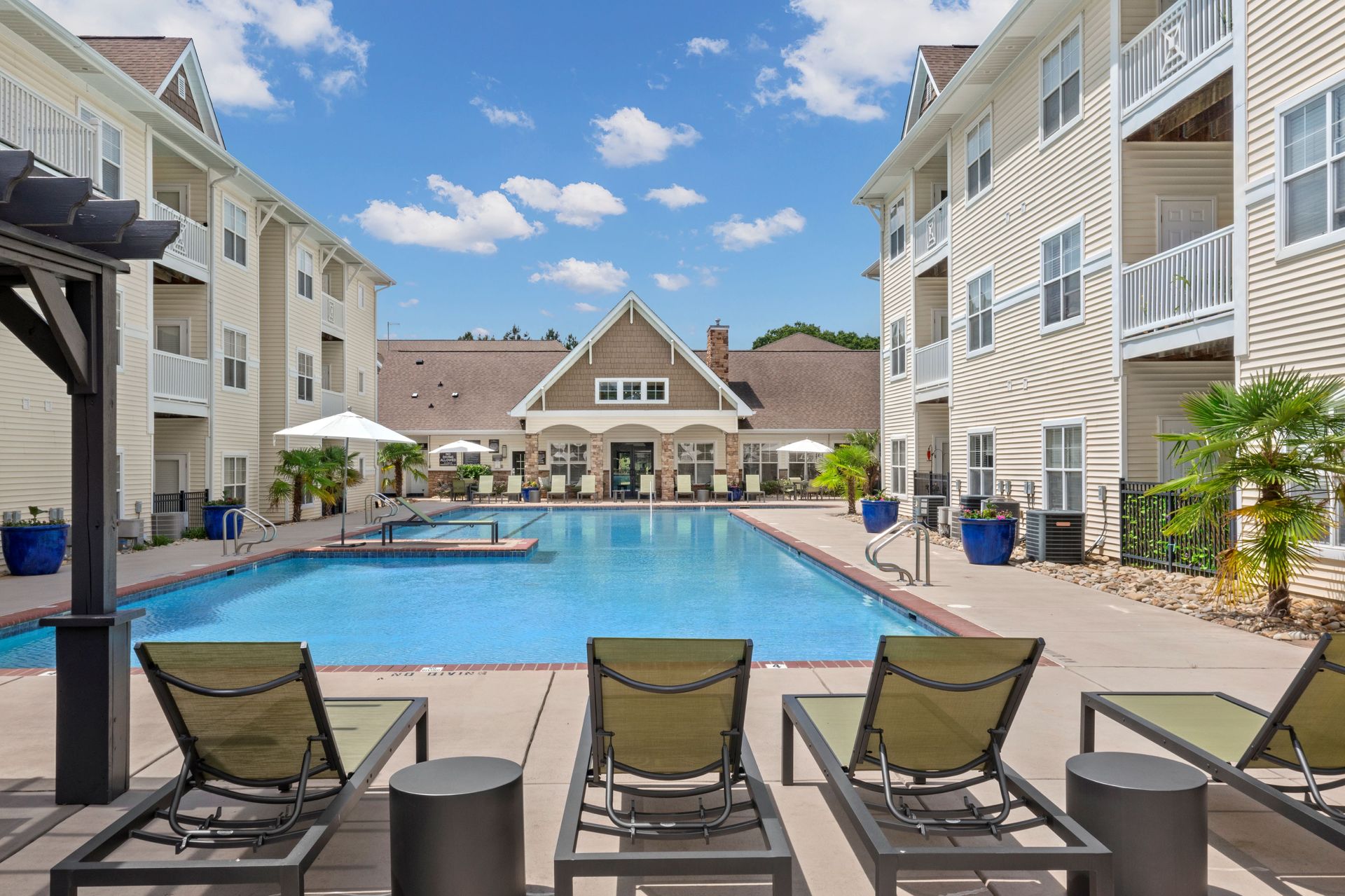 a large swimming pool is surrounded by chairs and umbrellas