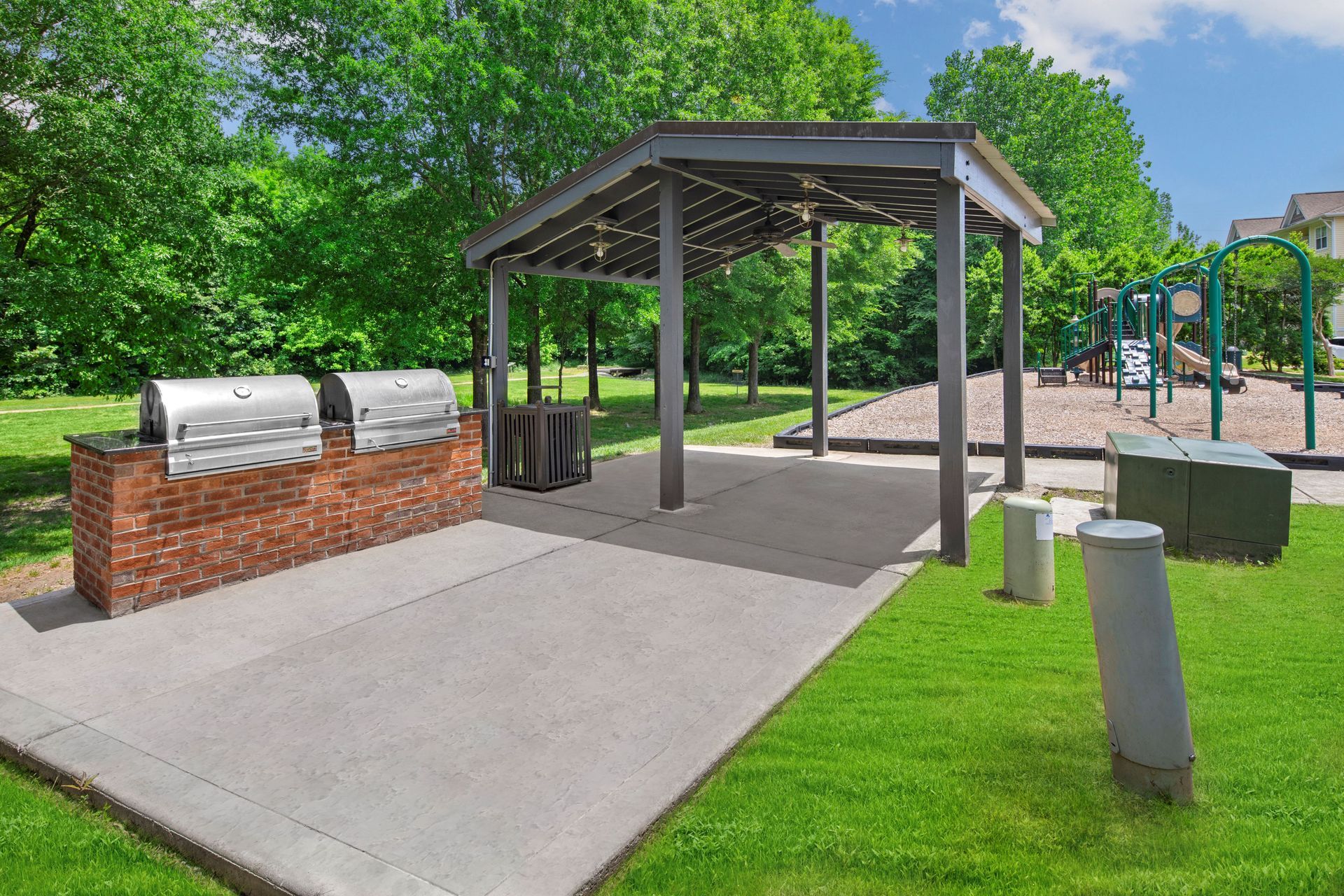 a covered area with a grill and a playground in the background