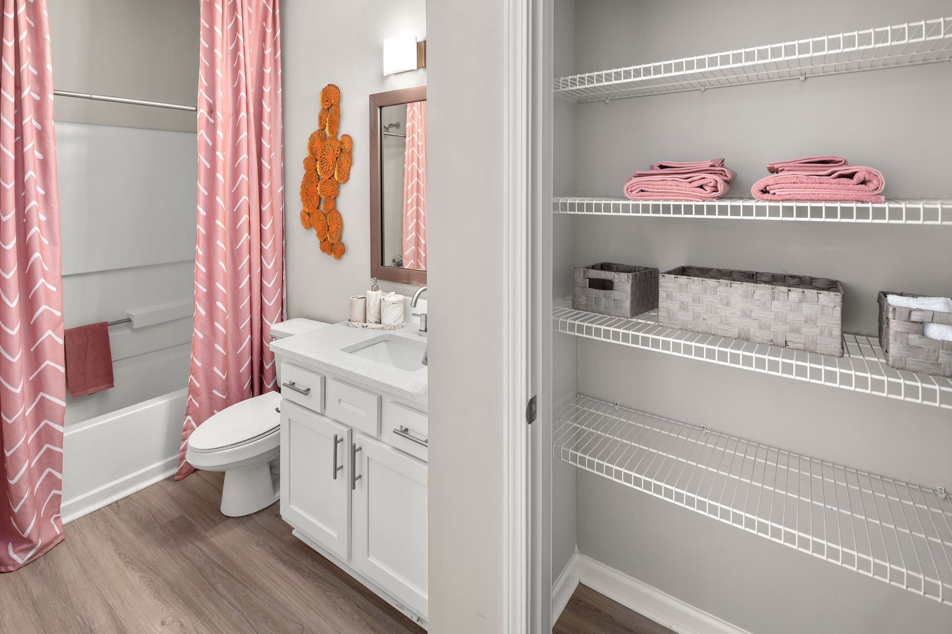 a bathroom with a pink shower curtain and white cabinets