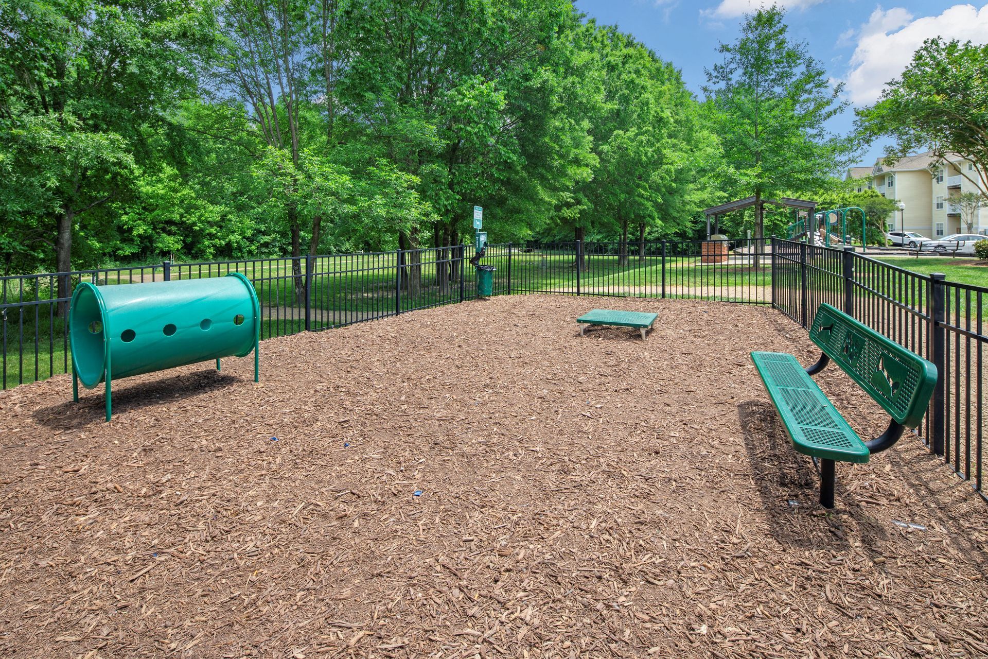 a dog park with a green tunnel and a bench