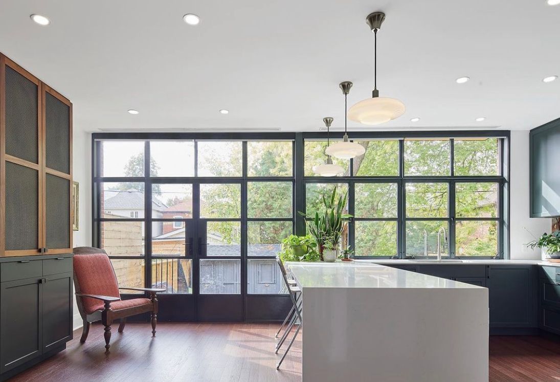 A kitchen with a large island and lots of windows.