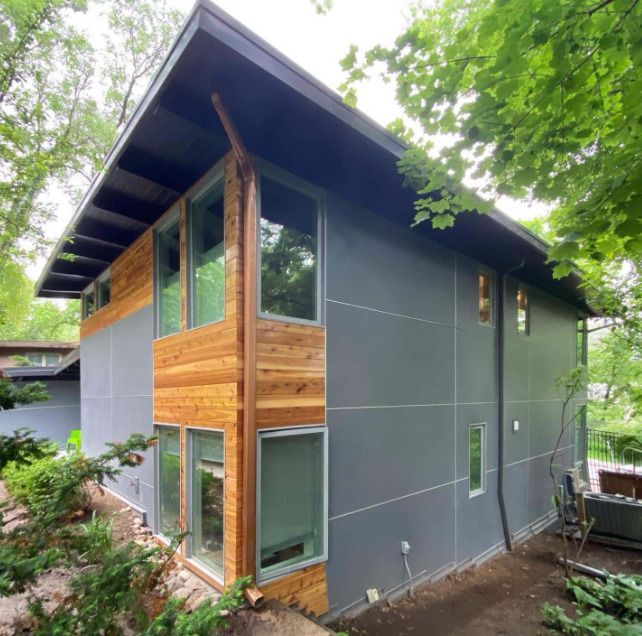 A house with a lot of windows is surrounded by trees