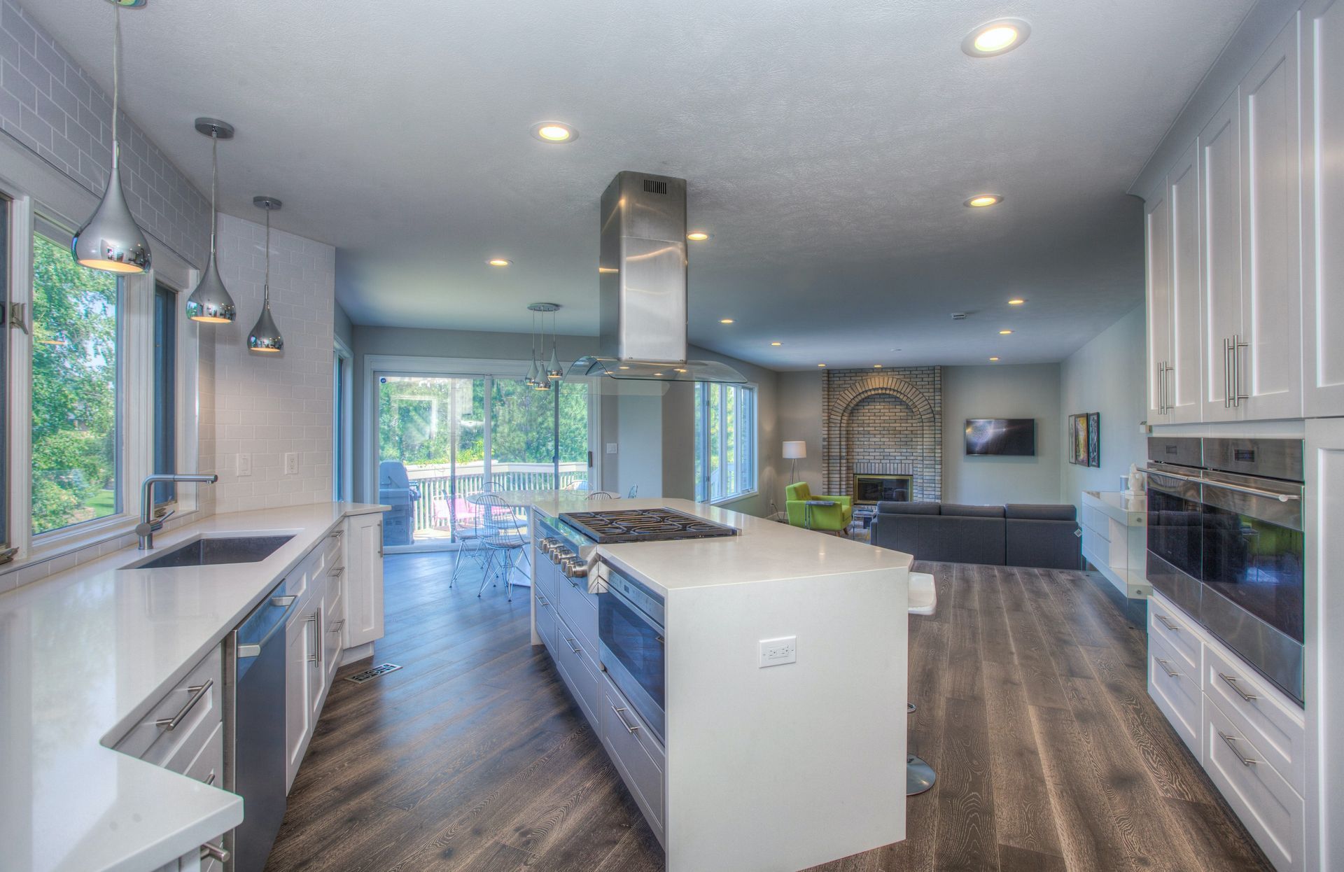 A kitchen with white cabinets and stainless steel appliances and a large island in the middle.