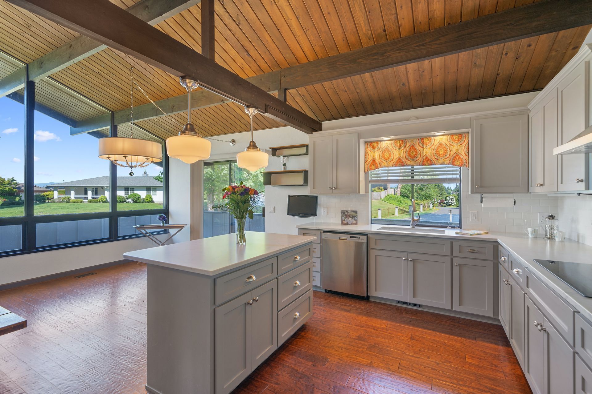 A kitchen with a large island in the middle and a wooden ceiling.