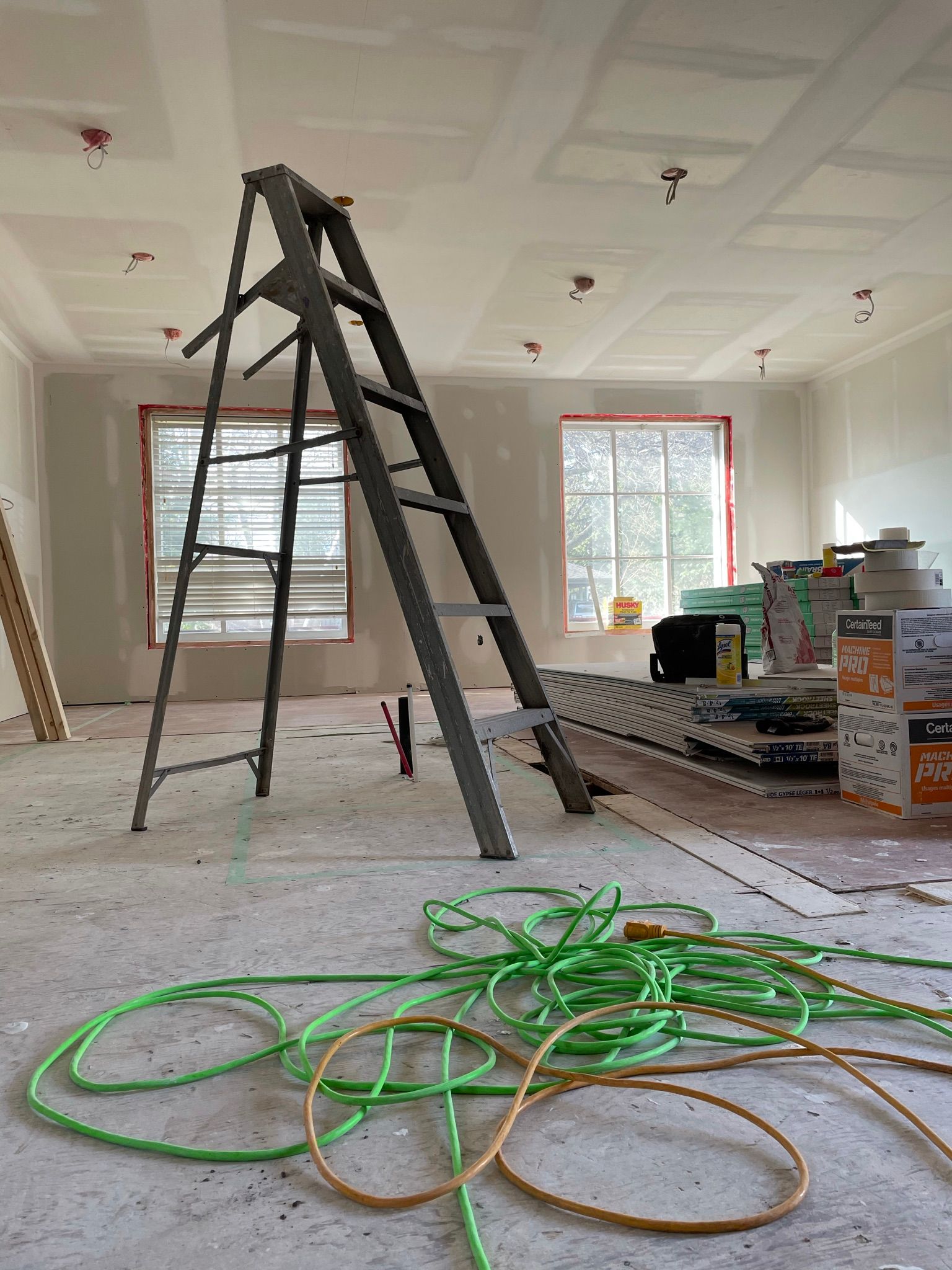 Interior construction site with a ladder, wiring, and unfinished walls and ceiling.