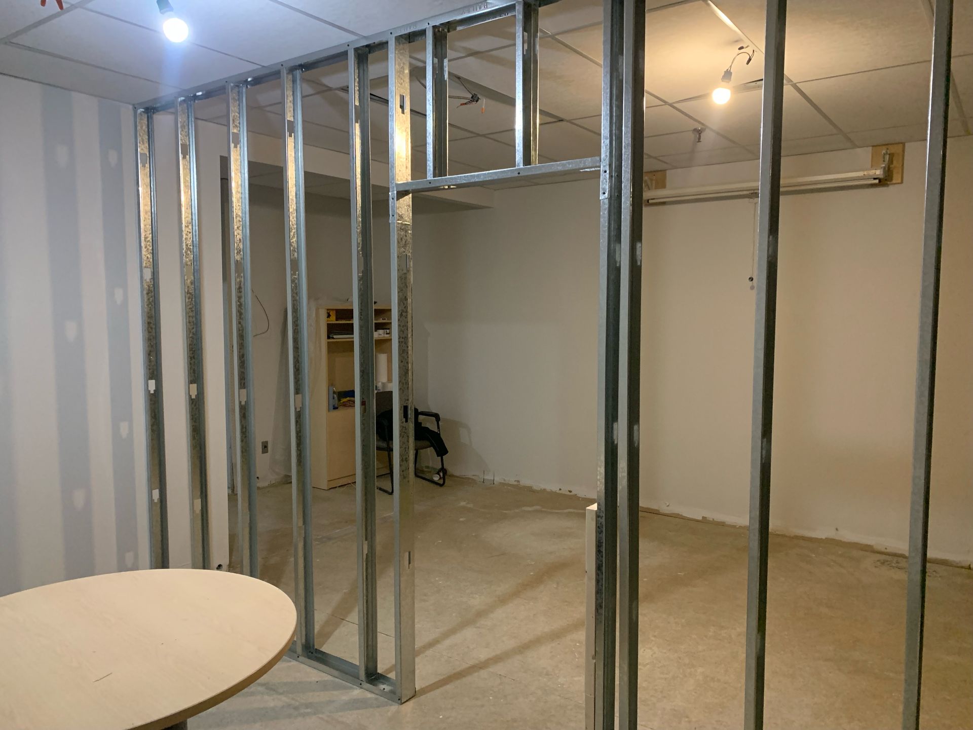 Interior with metal studs framing a room with an opening for a doorway; unfinished walls and floor.