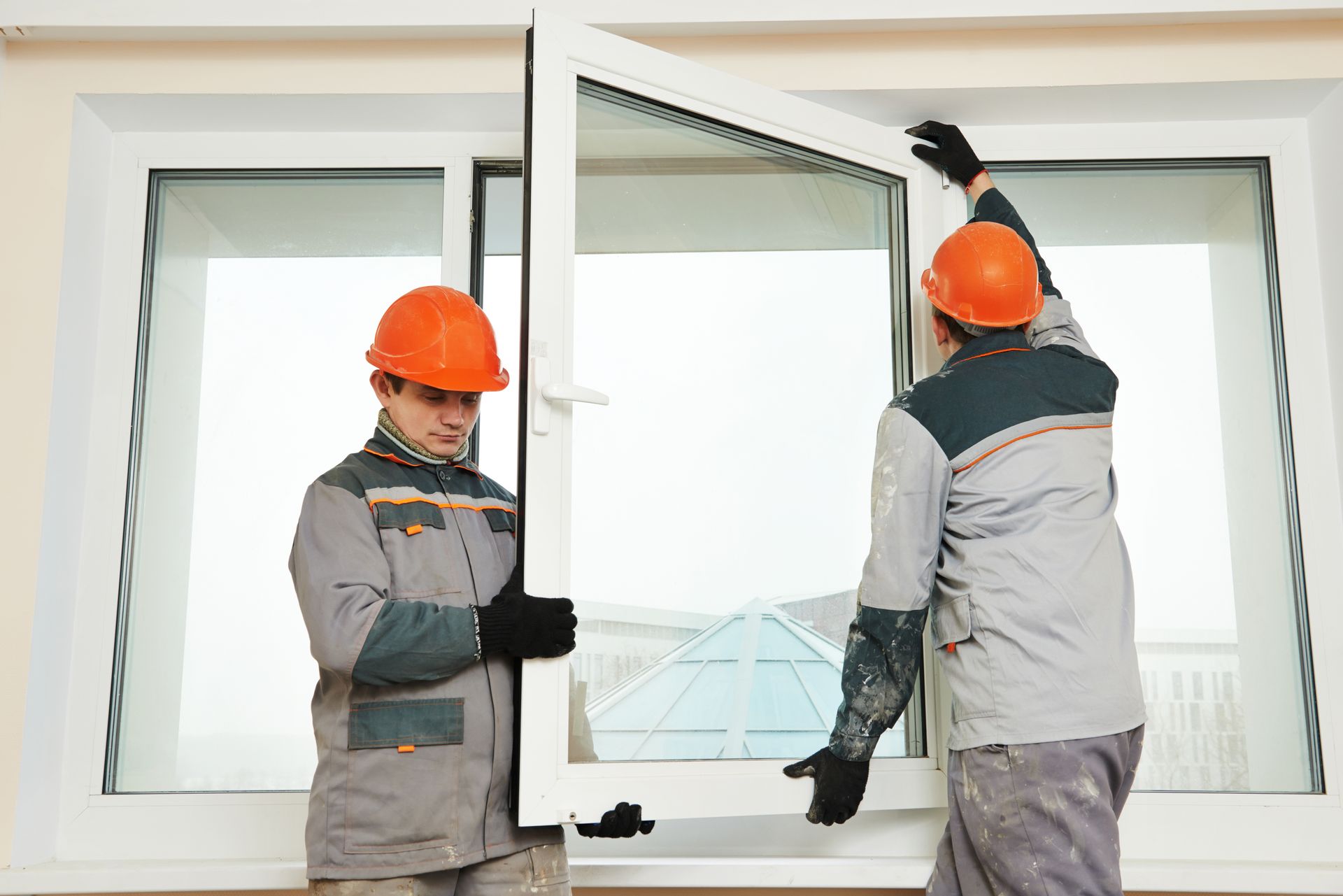 Two men are installing a window in a house.