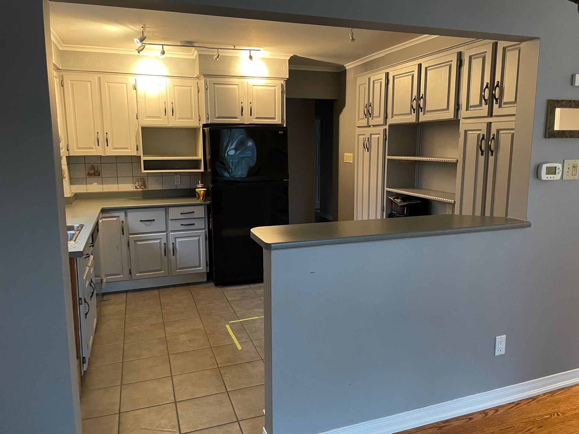 A kitchen with white cabinets and a black refrigerator